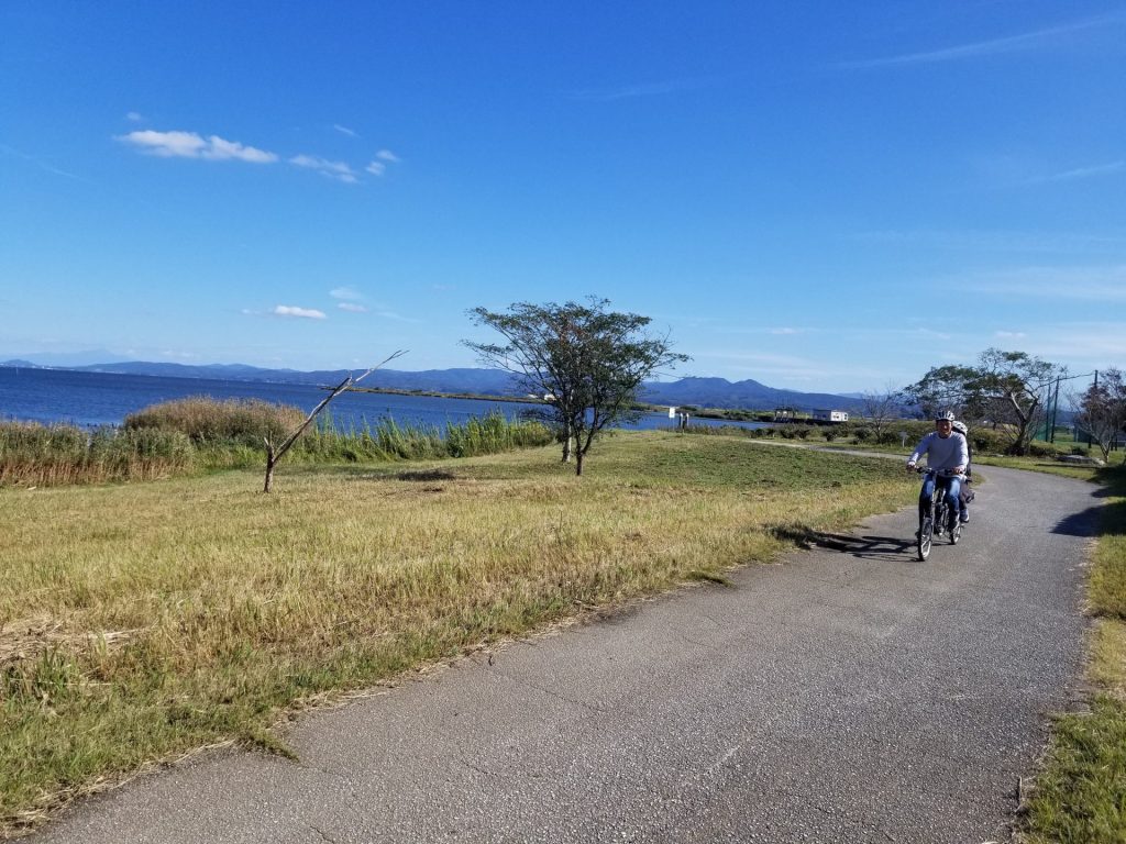 宍道湖を経背景にタンデム自転車に乗って走るペアの写真（帰り）